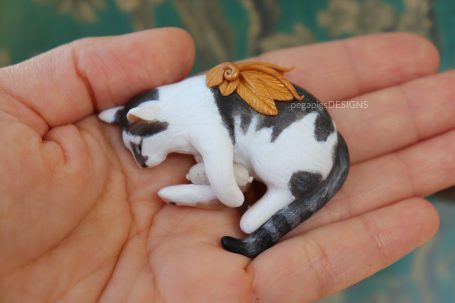 Schlafende Katzenfigur mit goldenen Flügeln