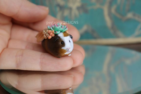 Mehrfarbige Meerschweinchen Figur mit goldenen Flügeln und Sukkulenten