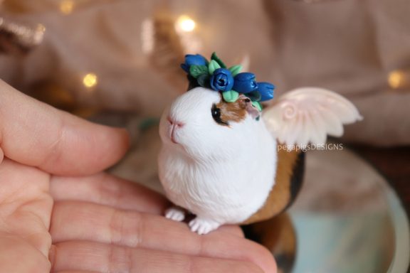 Dreifarbige Meerschweinchen Skulptur mit Flügeln und blauen Tulpen auf dem Kopf