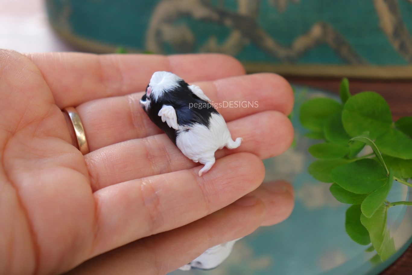 Premium Schwarz und weißes Meerschweinchen als Miniatur Skulptur mit kleinen Flügeln und gestreckten Hinterbeinen