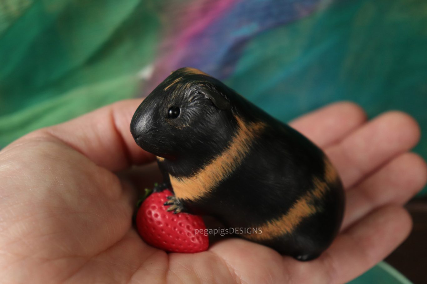 Premium Schwarz und braunes Meerschweinchen als Miniatur Skulptur mit einer Erdbeere
